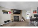 Open living area with a stone fireplace and mounted TV, adjacent to dining area and stairs at 3253 S Estes St, Lakewood, CO 80227