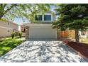 Home exterior displaying a wide driveway, stone accents, well-kept lawn, and partial view of the surrounding landscape at 1462 Marigold Dr, Lafayette, CO 80026