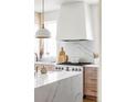 Close up of a modern gas range and hood with white countertops and marble backsplash at 1221 W 144Th Ct, Westminster, CO 80023