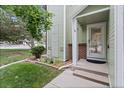 Inviting covered front porch with brick accents and a decorative glass door, surrounded by lush landscaping at 8997 W 88Th Ave, Westminster, CO 80021
