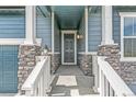 Inviting front porch featuring stone pillars, a modern entry door, and charming lantern-style lighting at 13342 E 110Th Way, Commerce City, CO 80022