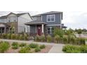 Inviting two-story home with gray siding, stone accents, a red front door and landscaped front yard with shrubs at 21854 E 9Th Pl, Aurora, CO 80018