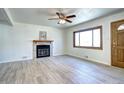 Spacious living room with light wood flooring, fireplace, large window and a ceiling fan for comfortable living at 6737 Lee St, Arvada, CO 80004