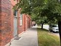 Brick exterior of building with sidewalk lined by grass and shady trees at 1111 Osage St # 7, Denver, CO 80204