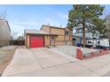 Traditional two-story home featuring a red garage door and a large driveway perfect for parking at 3977 S Pitkin Way, Aurora, CO 80013