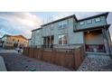 Back of the home featuring neutral siding, small trees, a brick foundation, and a cozy porch at 359 Courtfield Way, Castle Pines, CO 80108