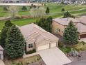 An aerial view of a well-maintained home near a golf course, boasting a spacious driveway and mature trees at 16631 Red Cliff Cir, Morrison, CO 80465
