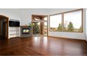 Bright living room featuring a fireplace, hardwood floors, mountain views, and a seamless indoor-outdoor flow at 11227 Explorers Run, Littleton, CO 80125