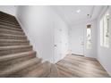 Bright entryway with hardwood floors, carpeted stairs, and white walls at 1182 Sugarloaf Ln, Erie, CO 80516