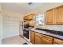 Kitchen featuring wooden cabinets, black countertops, and modern appliances at 2831 W Irvington Pl, Denver, CO 80219