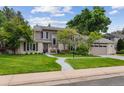 Charming home with a manicured lawn, mature trees, and a curved walkway leading to the front door at 5766 S Fulton Way, Greenwood Village, CO 80111