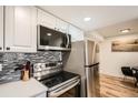 Modern kitchen featuring stainless steel appliances, white cabinets, and a stylish backsplash design at 10785 W 63Rd Pl # 108, Arvada, CO 80004
