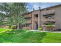 Multi-level condo with wood-style facade, multiple balconies, mature trees, and a well-maintained grassy lawn at 201 Wright St # 105, Lakewood, CO 80228
