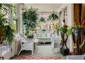 Relaxing sunroom filled with plants and wicker furniture, perfect for enjoying the outdoors at 1521 Pontiac St, Denver, CO 80220