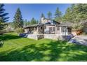 A multi-story home featuring stone accents, a spacious patio, and a well-maintained lawn with mature trees at 11531 S Deer Creek Rd, Littleton, CO 80127