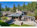 Beautiful exterior of a multi-story home showcasing a stone chimney and outdoor living space with patio furniture at 11531 S Deer Creek Rd, Littleton, CO 80127