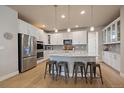 Modern kitchen with stainless steel appliances, white cabinetry, granite countertops, and large center island at 6747 W Jewell Pl, Lakewood, CO 80227