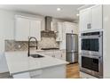 Bright kitchen with stainless steel appliances, stone backsplash, and white cabinets at 42976 Colonial Trl, Elizabeth, CO 80107