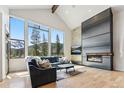 Sunlit living room with mountain view through large windows and modern fireplace at 427 Whispering Pines Cir, Breckenridge, CO 80424