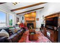 Spacious living room with exposed beam ceiling, fireplace, and large window offering abundant natural light at 214 Poppy St, Golden, CO 80401