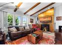 Bright living room featuring exposed beam ceiling, fireplace, and a large window, creating a warm and inviting atmosphere at 214 Poppy St, Golden, CO 80401