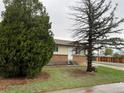 Charming single-story house showcasing lush front lawn and mature trees, creating a serene and inviting curb appeal at 405 Dogwood Ave, Brighton, CO 80601