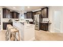 Gourmet kitchen featuring dark cabinetry, stainless steel appliances, granite countertops and bar seating at 15280 Bannock St, Broomfield, CO 80023