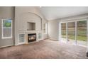 Open living room featuring a cozy fireplace, built-in shelving, a large window, and sliding doors to the backyard at 5755 S Zante Cir, Aurora, CO 80015