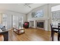 Spacious living room features a fireplace, large windows, hardwood floors, and vaulted ceilings at 12879 E Dickensen Pl, Aurora, CO 80014