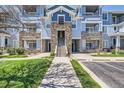 A walkway leads to a blue and grey stone apartment building on a clear day at 5255 Memphis St # 311, Denver, CO 80239