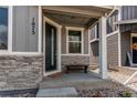 Inviting covered front porch with stone accents, bench seating, and modern design at 1075 Spartan Ave, Berthoud, CO 80513