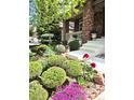 Landscaped front yard with colorful flowers, green bushes, and a brick home entrance at 7132 S Tempe Ct, Aurora, CO 80016