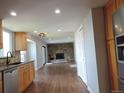Spacious living room open to kitchen featuring a cozy stone fireplace and hardwood floors at 7753 W Plymouth S Pl, Littleton, CO 80128