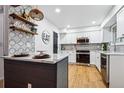 Modern kitchen featuring white cabinets, stainless steel appliances, and a stunning tile backsplash at 6885 E Briarwood Cir, Centennial, CO 80112