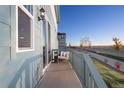 Outdoor balcony area featuring a chair, table, and wooden railing with scenic neighborhood view at 21104 E 63Rd Dr, Aurora, CO 80019