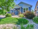 Beautifully landscaped front yard featuring a lush green lawn, rock beds, and mature trees at 5309 W Hoover Dr, Littleton, CO 80123