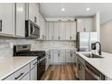Modern kitchen with stainless steel appliances, gray cabinets, tile backsplash, and quartz countertops at 9376 Yampa Ct, Commerce City, CO 80022