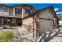 Angled view of charming tan home with brick accents and a three car garage and front porch at 18885 E Union Dr, Aurora, CO 80015