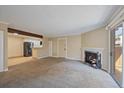 Bright living room with a cozy fireplace, wood beam, and natural light from sliding doors at 3332 S Ammons St # 103, Lakewood, CO 80227