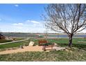 Scenic backyard view featuring a bench, large tree, flower planter and water view at 5425 County Road 32 # 14, Mead, CO 80504