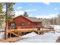 Spacious wooden deck offering a relaxing outdoor space with wood piles ready for the fireplace and views of the surrounding landscape at 9239 Black Mountain Dr, Conifer, CO 80433
