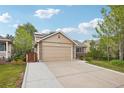 Tan home with a two car garage, stone accents and a well manicured front yard at 12753 Buckhorn Creek St, Parker, CO 80134
