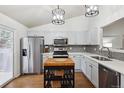 Kitchen features white cabinets, stainless steel appliances, tile backsplash, and hardwood floors at 12753 Buckhorn Creek St, Parker, CO 80134