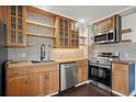 Modern kitchen with stainless steel appliances, wooden cabinets, and open shelving at 11651 Pennsylvania St, Northglenn, CO 80233
