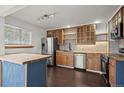 Modern kitchen with island, stainless steel appliances, wood cabinets, and hardwood floors at 11651 Pennsylvania St, Northglenn, CO 80233