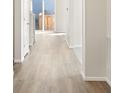 Hallway features light wood floors and white trim leading to a bright, sunlit exit at 9089 Pitkin St, Commerce City, CO 80022
