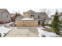 Charming two-story home featuring a three-car garage, stone accents, and a well-maintained front yard with wintery landscaping at 477 Saber Creek Dr, Monument, CO 80132