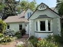 Close-up of the home's exterior with brick accents, a bay window, and colorful flower beds at 6375 E 6Th Avenue Pkwy, Denver, CO 80220