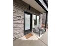 Home's inviting porch area featuring gray chairs, stone accents, and a modern, dark-framed front door at 1472 Yates St, Denver, CO 80204