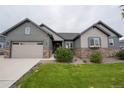 Charming home featuring a two-car garage, stone accents, a well-manicured lawn, and tasteful landscaping at 11259 Kalispell St, Commerce City, CO 80022